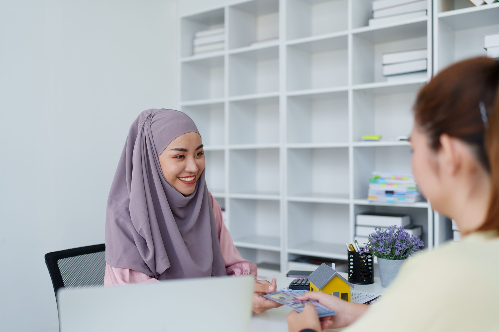A female Muslim bank employee, making an agreement on a residential loan with a customer.
